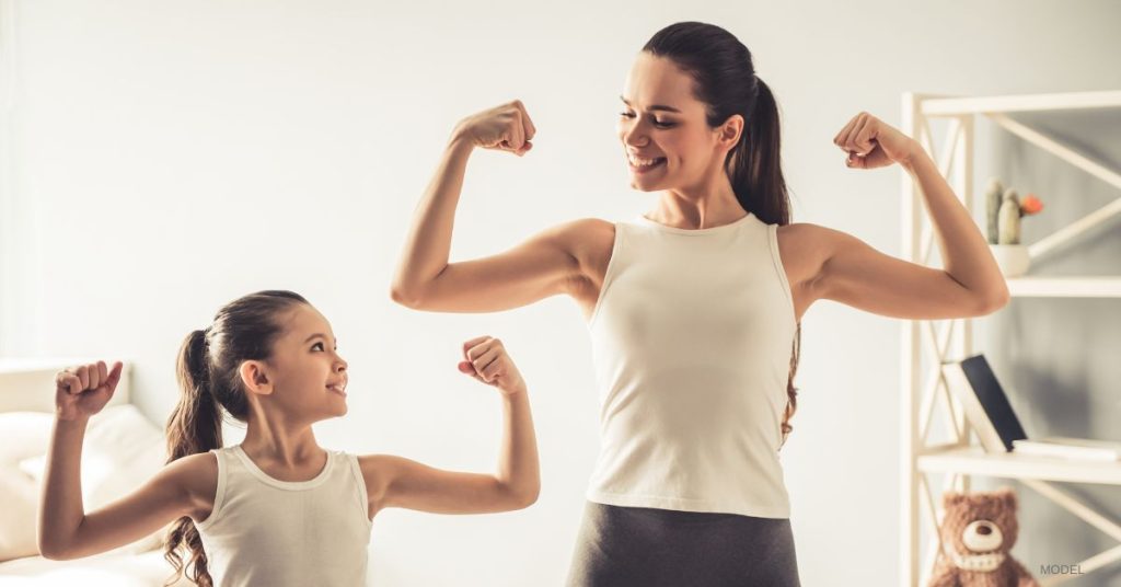 mom and daughter flexing their muscles. (Models)